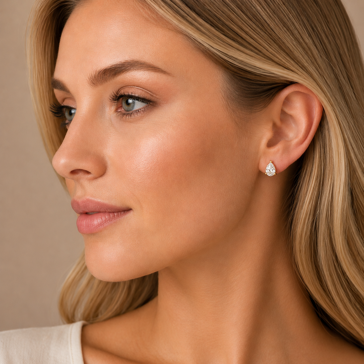 Close-up of a woman wearing a diamond earring against a neutral background